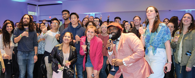 Staff members and Class of 2019 students raise glasses of champagne and smile